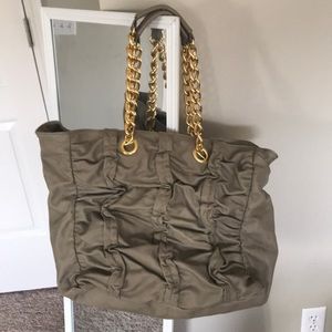 Stylish taupe large back with gold chain accent.